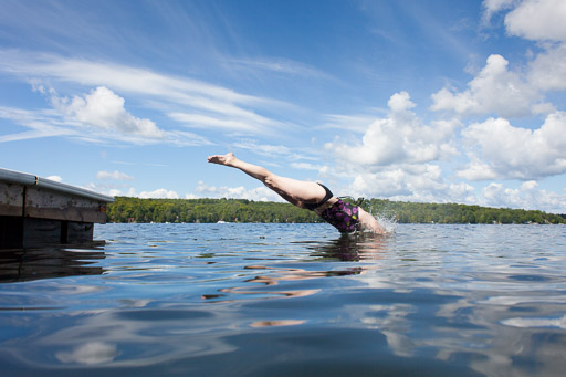 woman diving into summer cottage lake woman diving into lake