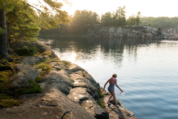 Girl in bathing suit on the rocky shore of lake near Killarney Provincial Park