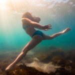 Woman in bikini diving exploring shallow blue green waters of Lake Ontario