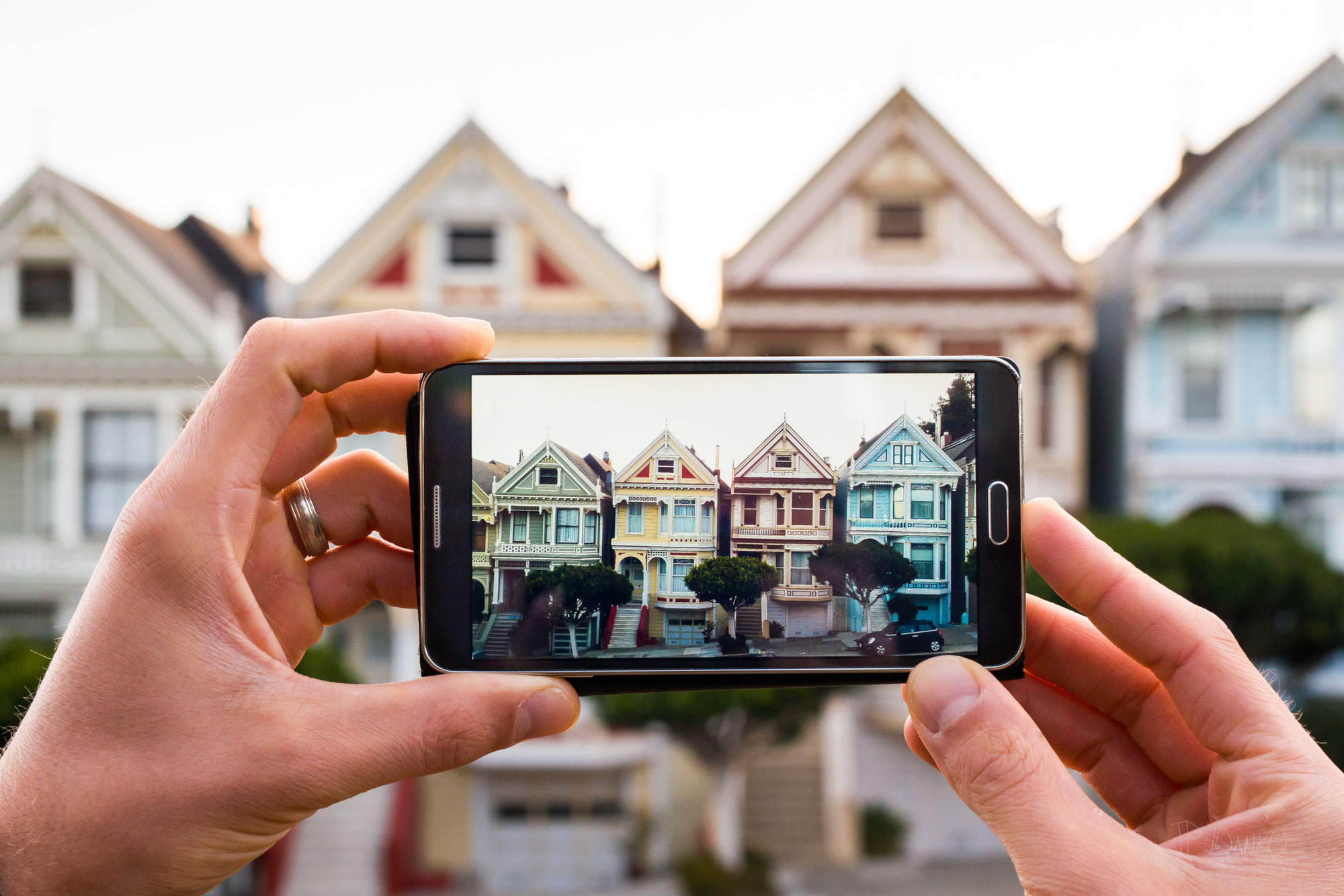 Man using a smartphone to photograph the "Painted Ladies" homes in San Francisco
