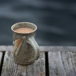 Coffee mug on a weathered cottage dock in early morning on summer day.