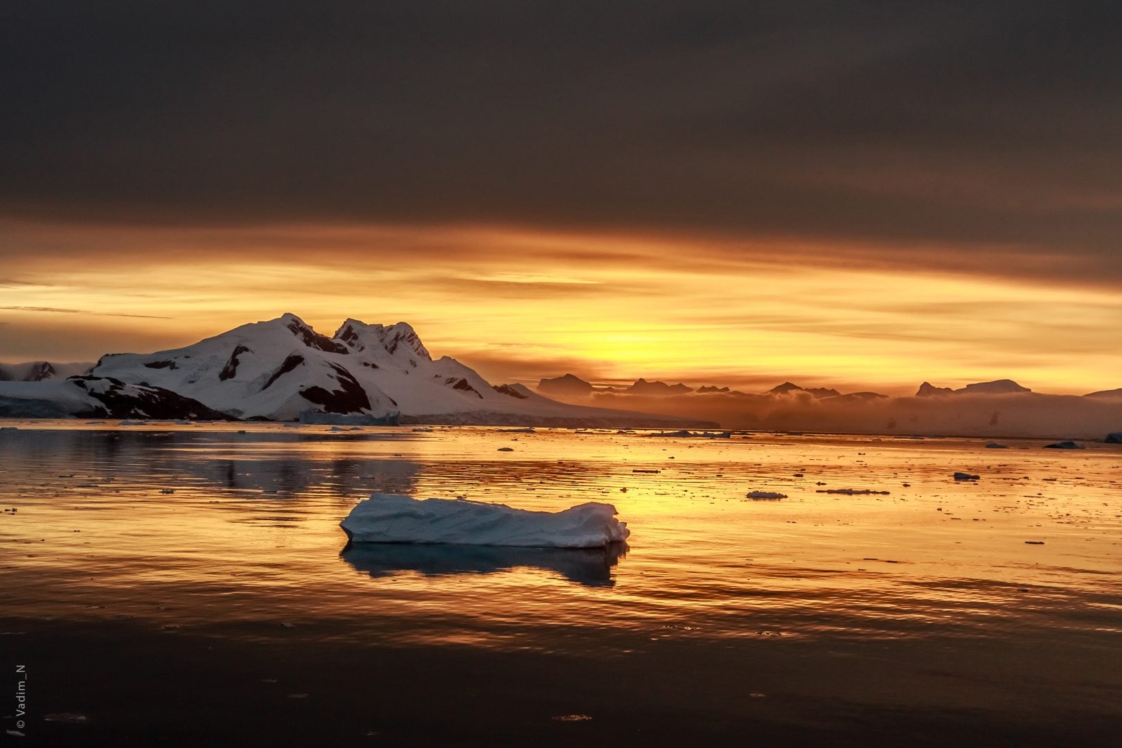 Sunset over the lagoon with drifting icebergs and snow mountains in the background, Lemaire Channel, Antarctica