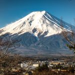 Tourists are taking photos of Mount Fuji through holes in the screen meant to deter them