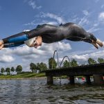 Young female triathlete jumping into a lake