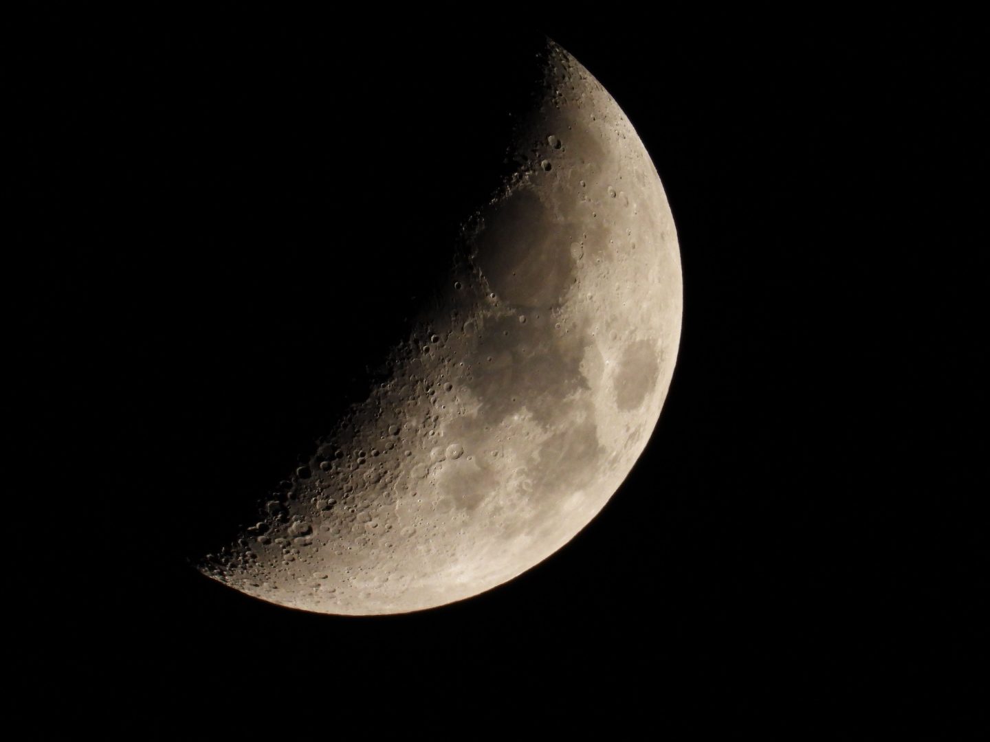 A close-up of a crescent moon with detailed craters against a black night sky.