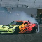 Dynamic shot of a colorful sports car drifting in a race with smoke and spectators in the background.
