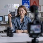 Young Asian woman designer,photographer blogger influencer filming teaching camera tutorial while looking at camera shooting education tutorial vlog training filming video course for social media at studio.