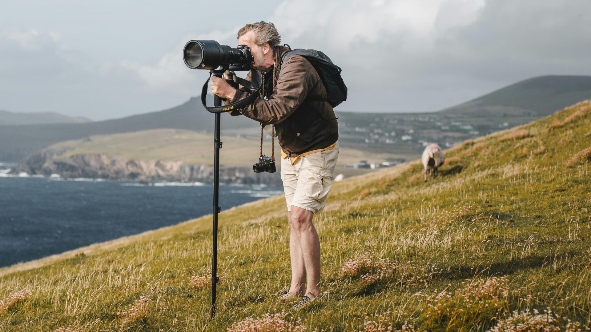 Photographer with a camera on tripod capturing scenic coastal views, highlighting the essence of landscape photography.
