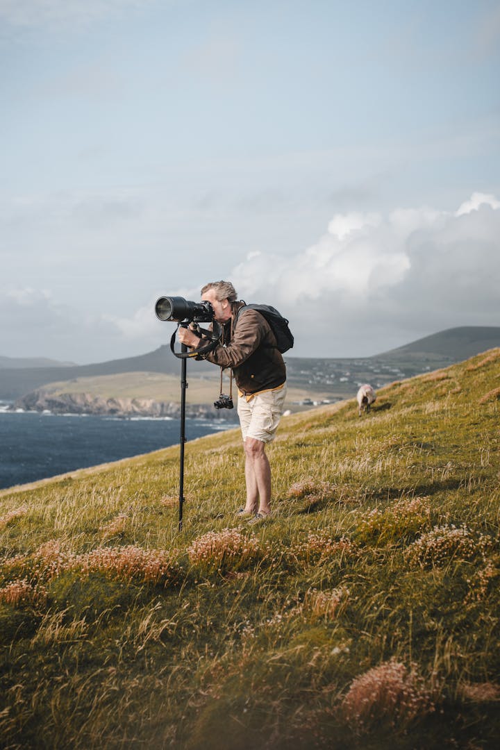 Photographer with a camera on tripod capturing scenic coastal views, highlighting the essence of landscape photography.