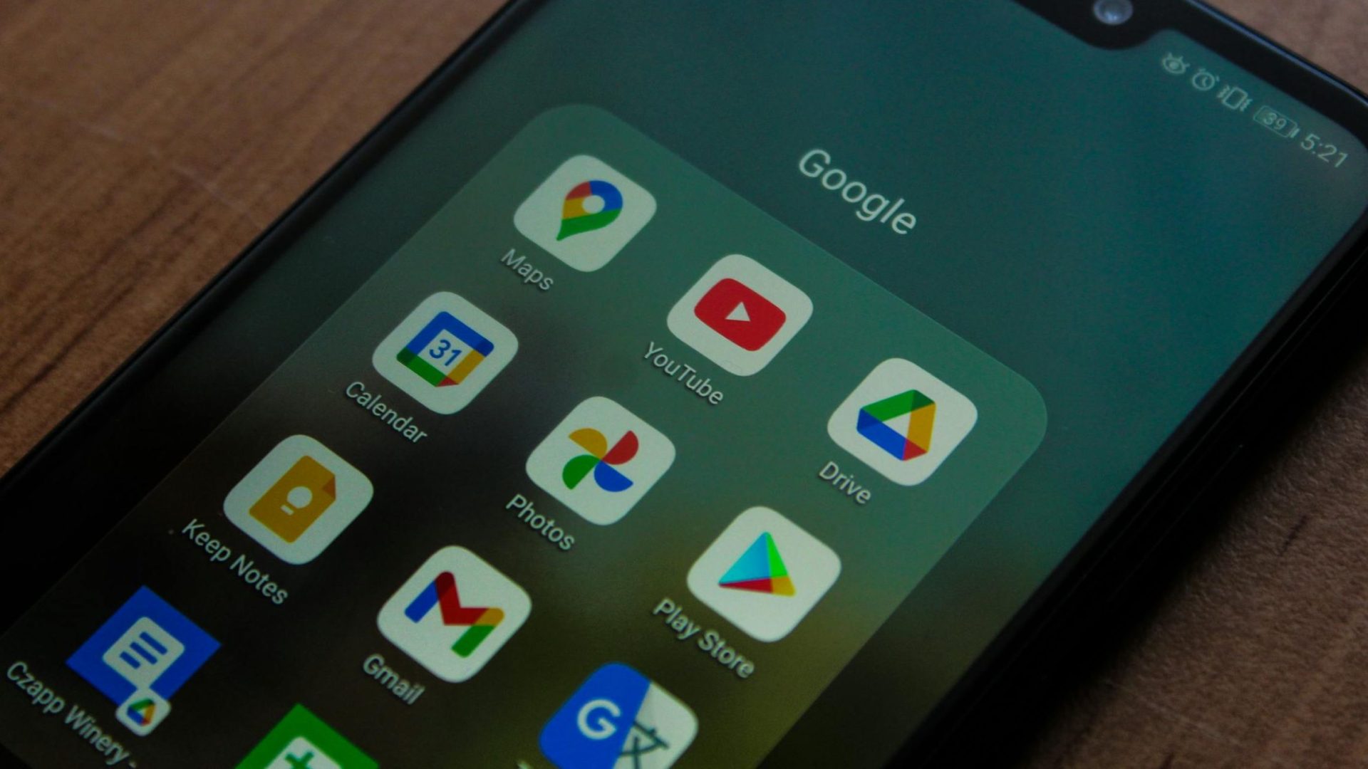 Close-up of a smartphone showing various Google apps on its screen.