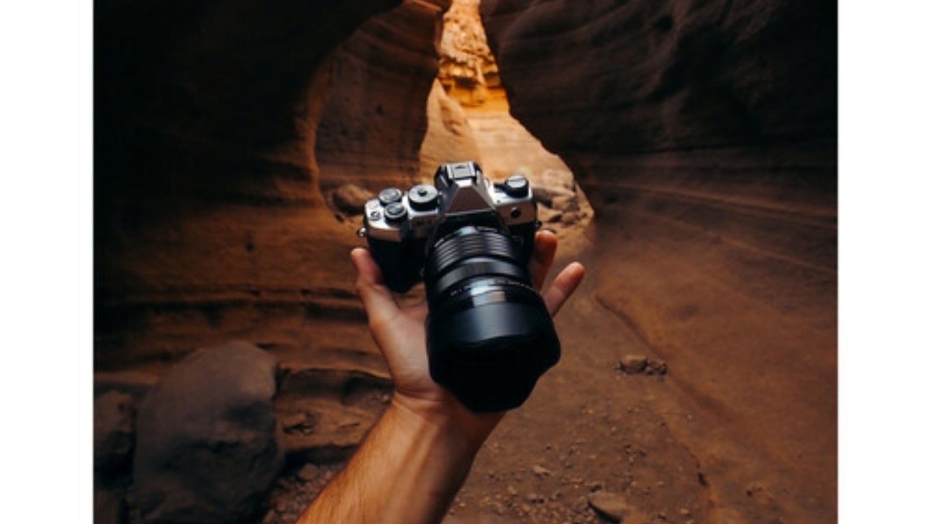 A person holding the OM SYSTEM OM-5 Mark II camera in a rocky canyon, highlighting the camera’s compact size and suitability for outdoor photography.