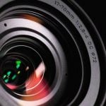 A close-up shot of a camera lens with intricate reflections, showcasing the precision and detail essential for capturing microscopic images with clarity and accuracy.