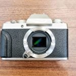 A top-down shot of the Fujifilm X-T1 mirrorless camera with the lens removed, highlighting its APS-C sensor. The classic silver-and-black body and textured grip reflect the retro-inspired design Fuji is known for.