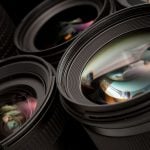 A detailed view of several camera lenses stacked together, showcasing their intricate lens elements and the various coatings reflecting light, highlighting their role in capturing stunning photographs with incredible detail and clarity.