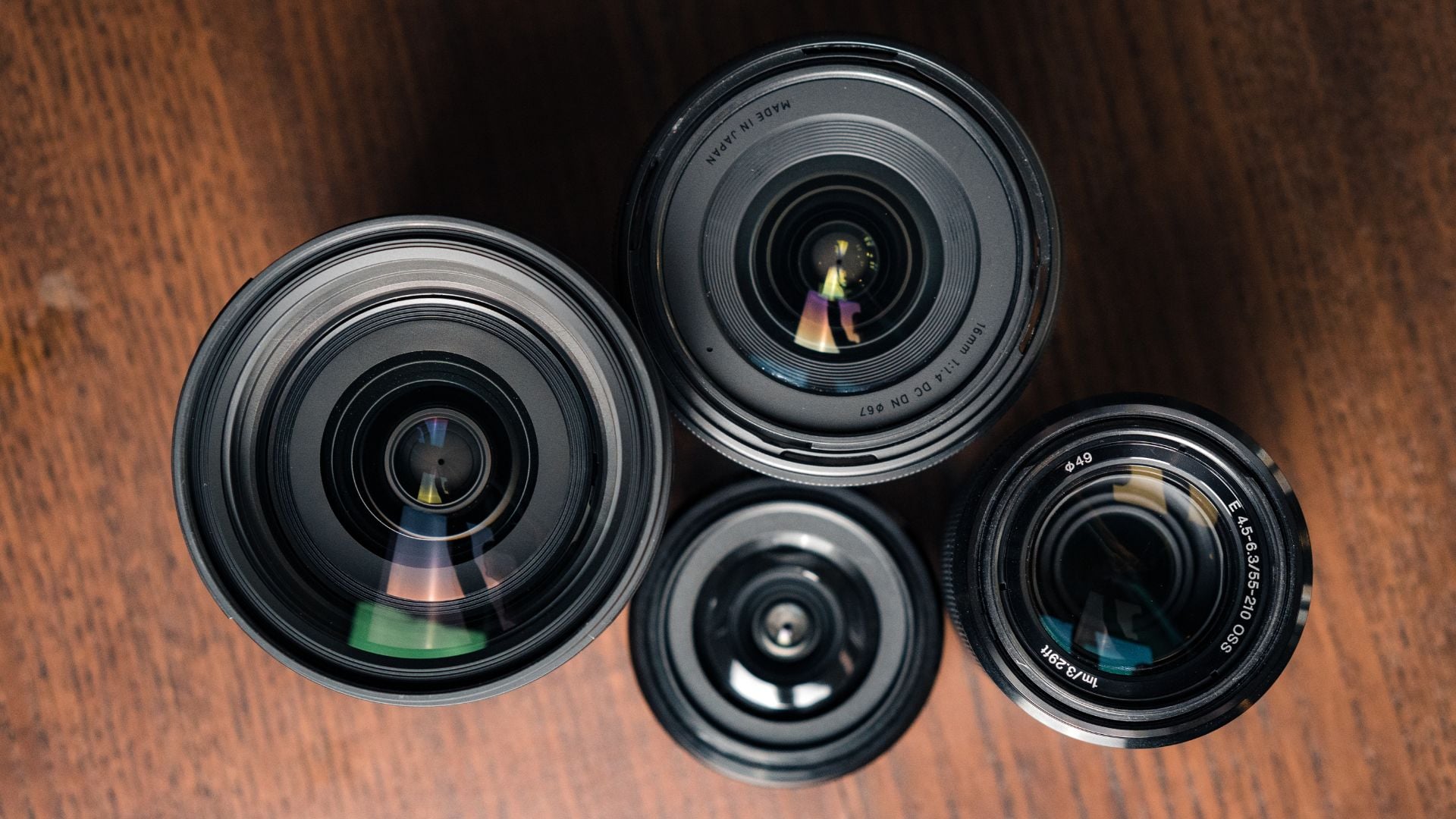 A variety of camera lenses arranged neatly on a wooden surface, focusing on their sleek design and the precision in their construction, representing the evolution of photography through their powerful optical performance.