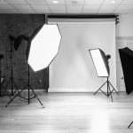 A monochrome image of a photography studio setup, with lights and reflectors arranged around a backdrop, showcasing the controlled lighting environment for corporate portraits.