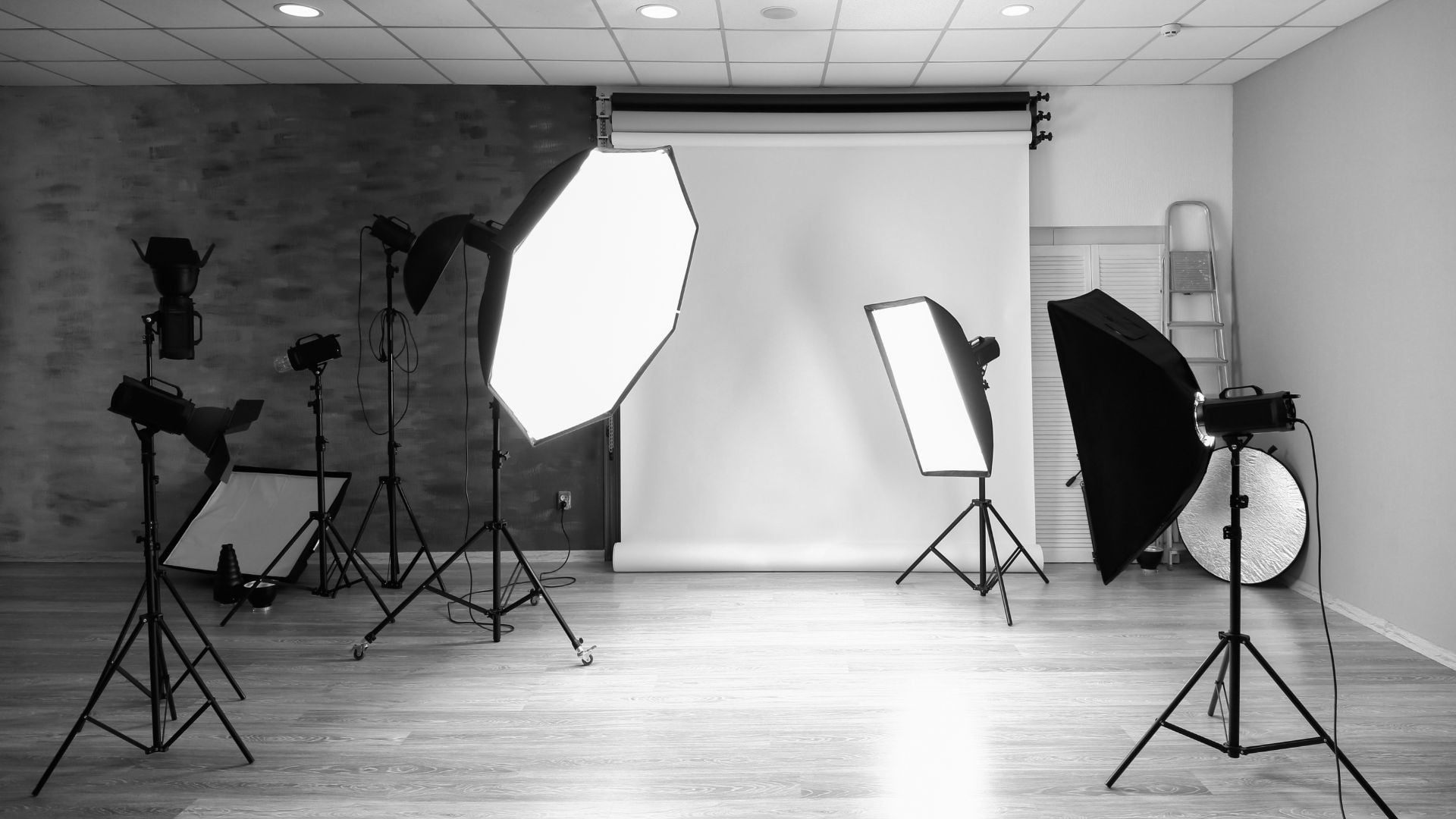 A monochrome image of a photography studio setup, with lights and reflectors arranged around a backdrop, showcasing the controlled lighting environment for corporate portraits.