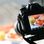A camera capturing a close-up shot of a plate of shredded carrots and apples with a soft background.