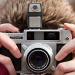 Close-up of an old-fashioned film camera with an analog lens, focusing on its mechanical details and vintage look.