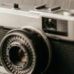 A classic film camera with a manual shutter and dial controls, evoking a retro photographic style.