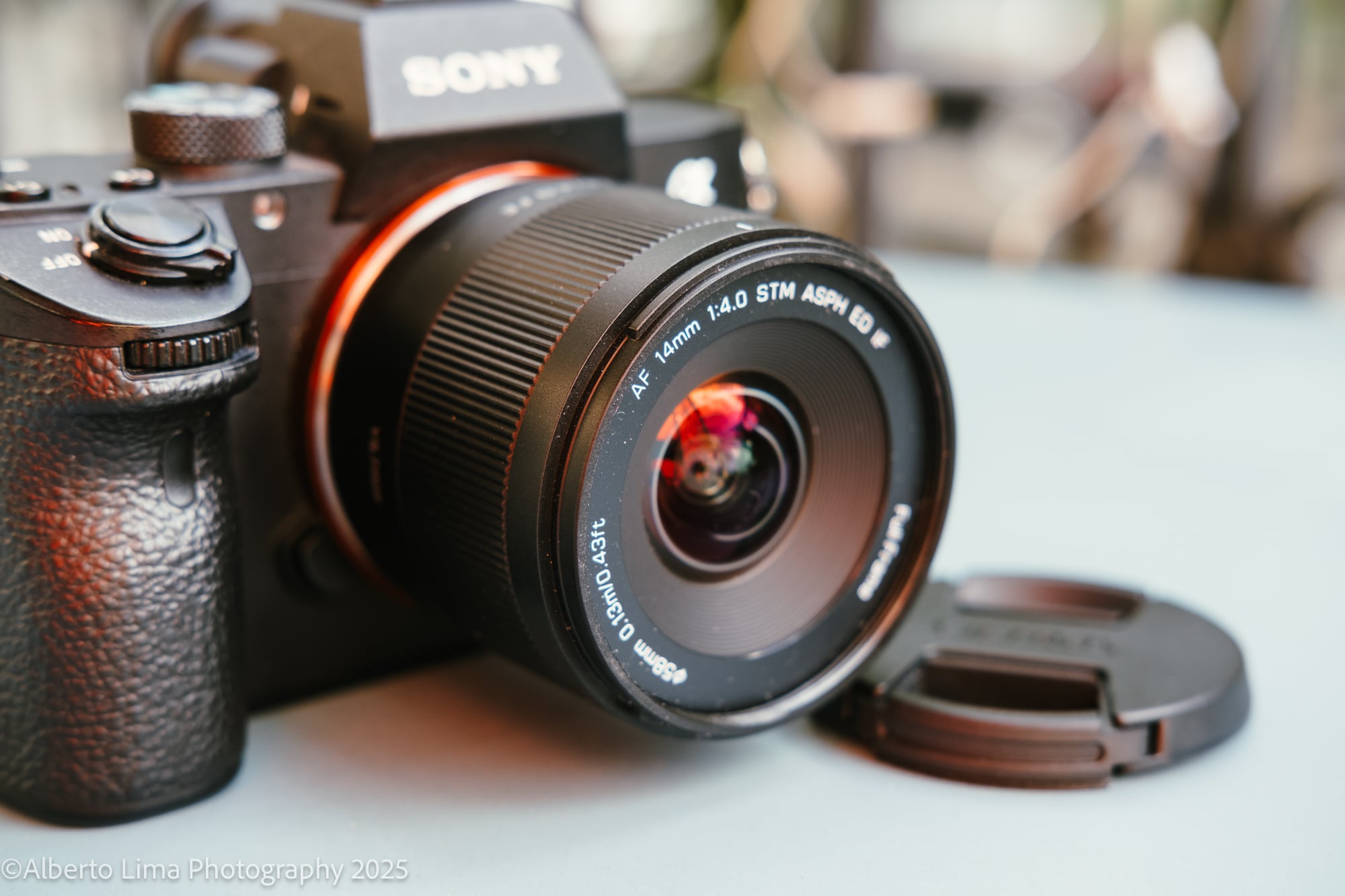 The Viltrox AF 14mm F4 Air lens paired with the Sony a7III on a blue table.