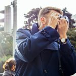 Man photographing in city against clear sky