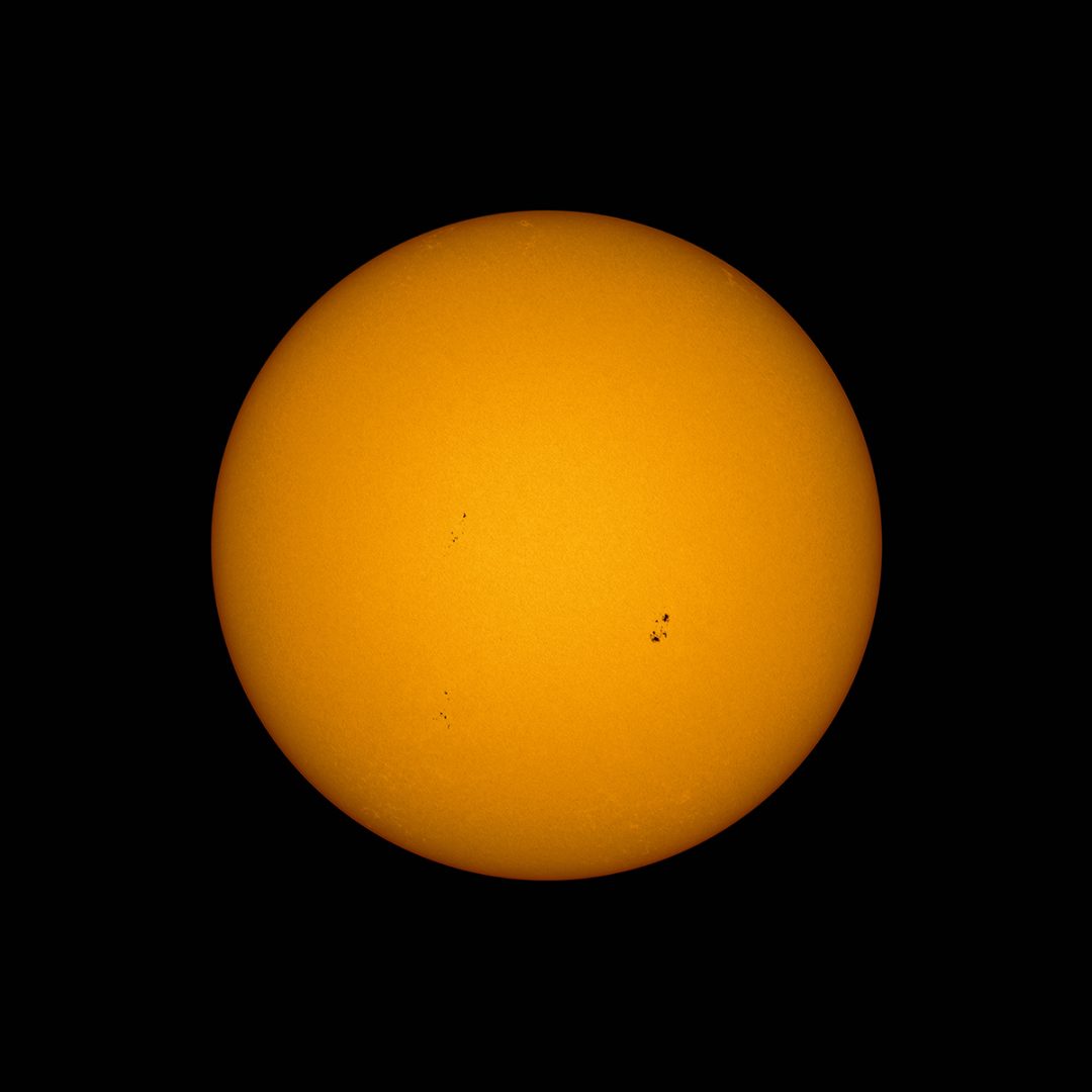 Photograph the sunspots with a telephoto lens and a solar filter