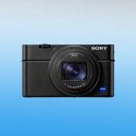 Front view of Sony RX100 VII compact camera featuring Zeiss Vario-Sonnar T* lens with f/2.8-4.5 aperture, blue Zeiss badge, textured body, and premium black finish on gradient background.