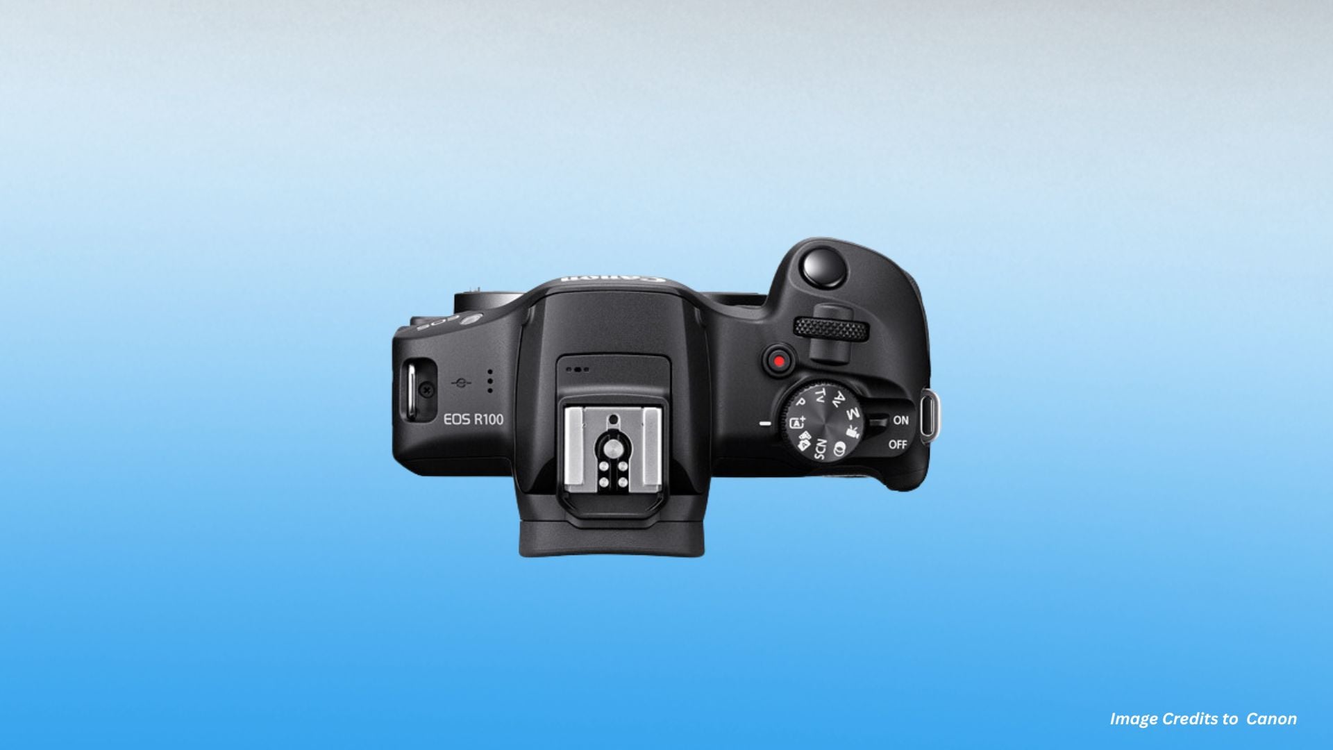 Top-down view of Canon EOS R100 showing EOS R100 branding, hotshoe mount, mode dial, power switch, record button, and minimal top plate design.