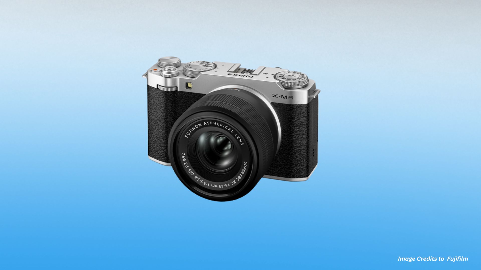 Three-quarter angled view of silver Fujifilm X-M5 with XC 15-45mm f/3.5-5.6 OIS lens showing compact form factor and classic rangefinder-style design aesthetic.