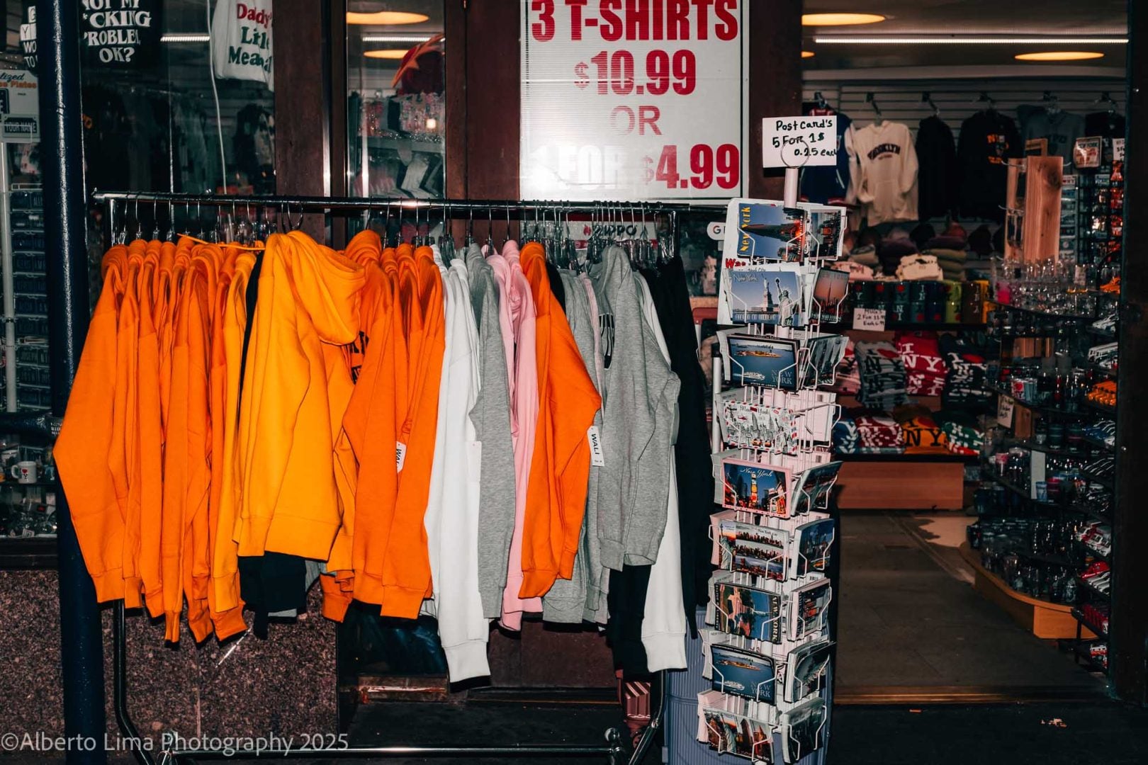 A souvenir shop in New York City with brightly colored sweat shirts and postcards on display. 