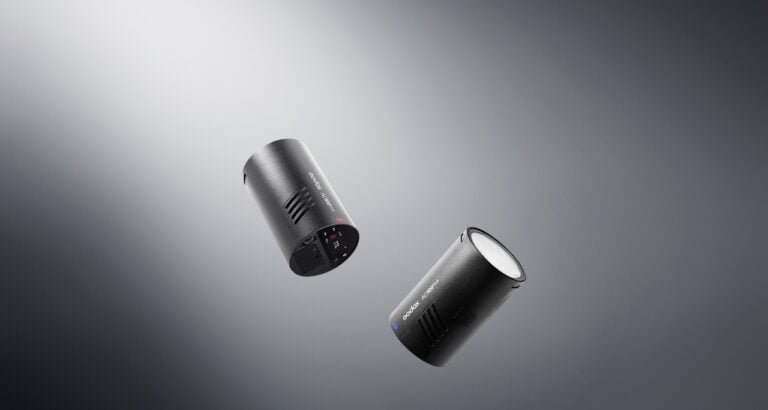 Two Godox AD100Pro II strobe lights suspended against a white and gray background.