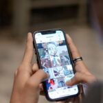 Hand scrolling through Instagram profile feed displaying photo gallery in grid layout for social media content management and portfolio review