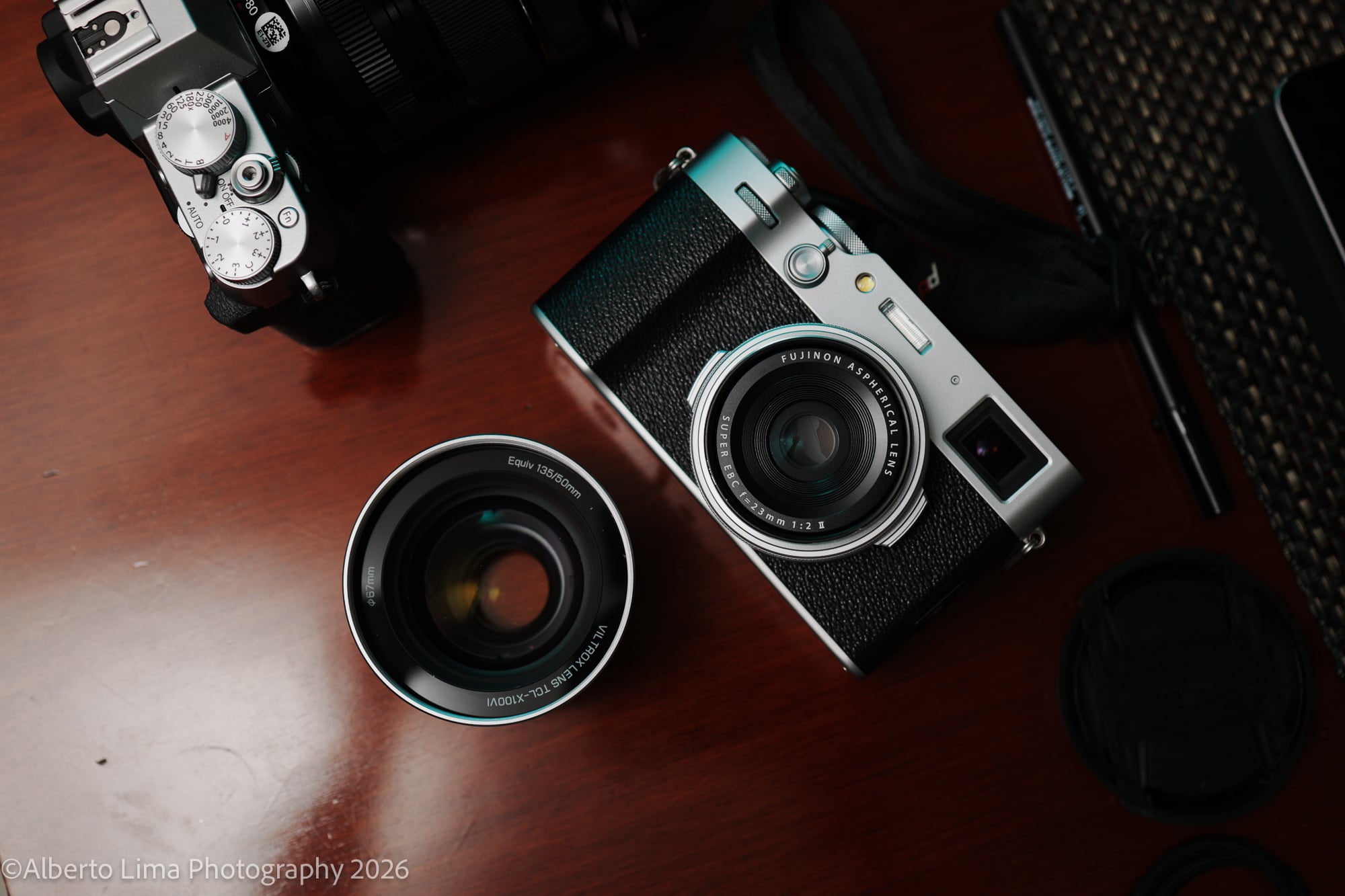 A Fujifilm X100VI pictured with the Viltrox TCL-X100VI on a cherry-colored wooden table top.
