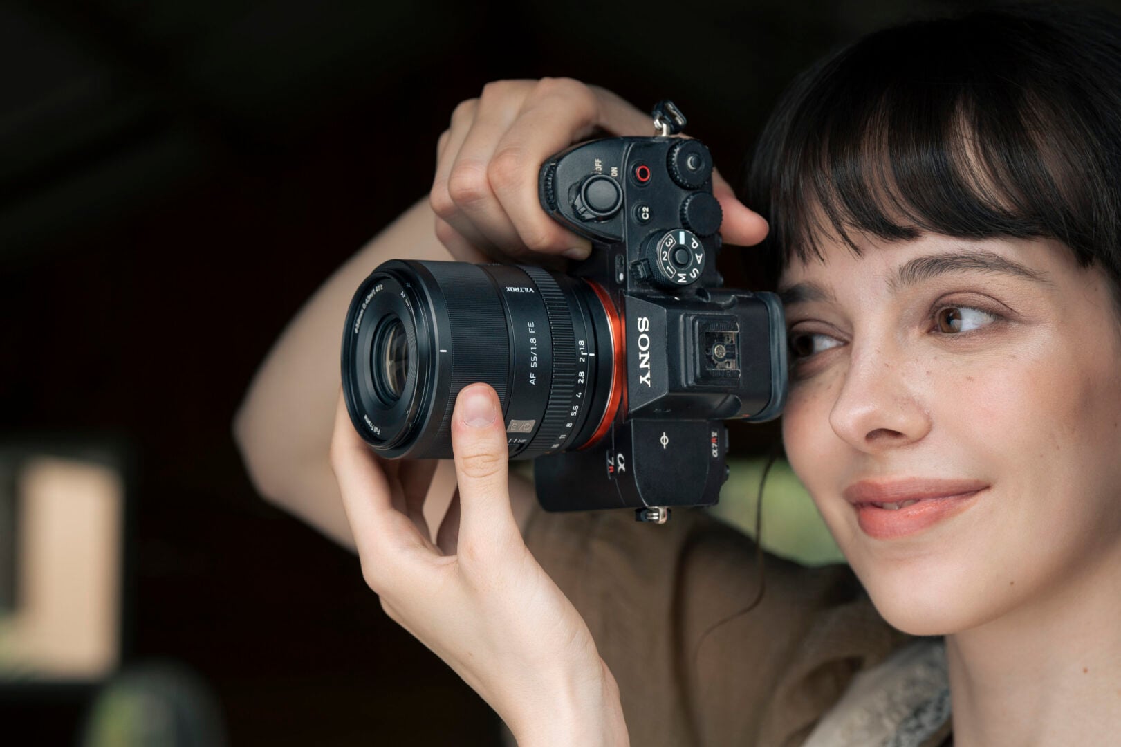 A woman holding a Sony camera with the Viltrox AF 55m F1.8 EVO.