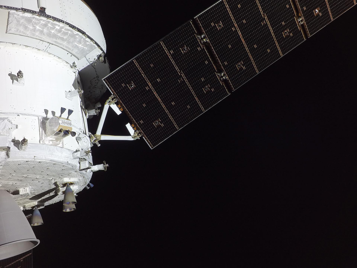 NASA’s Orion spacecraft pictured from one of the cameras mounted on its solar array wings. The service module is prominently featured in this image, showing a portion of the orbital maneuvering system engine and three of eight auxiliary thrusters. Credit: NASA