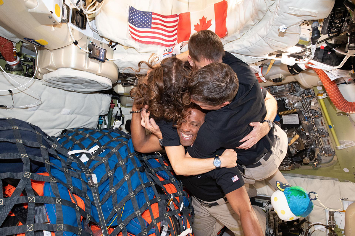 A group hug inside the Orion spacecraft on their way home. Credit: NASA