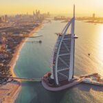 Aerial view of Burj Al Arab Jumeirah Island or boat building, Dubai Downtown skyline, United Arab Emirates or UAE. Financial district in urban city. Skyscrapers at sunset.