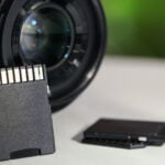 SD memory cards and photo camera on white table, closeup