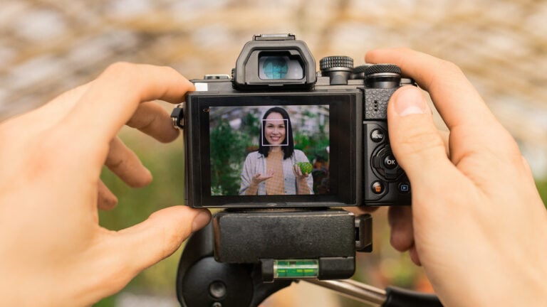 Unrecognizable camera operator shooting video with Asian farmer telling about healthy organic food for blog