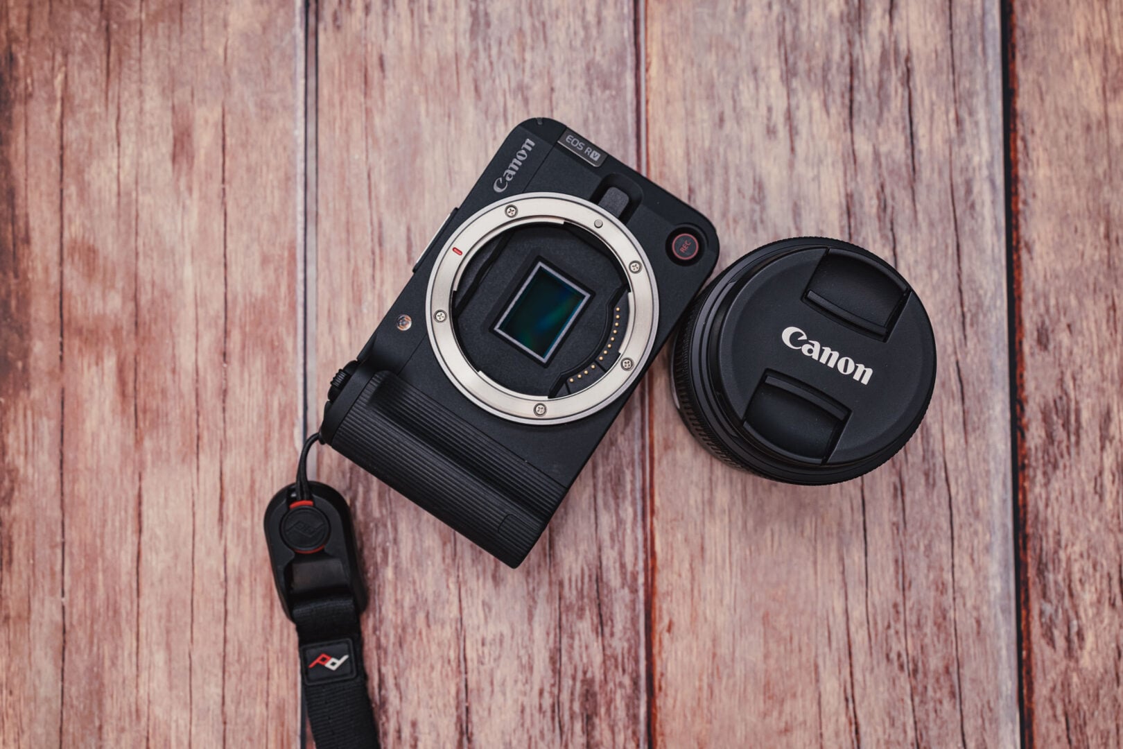 The Canon EOS R50V with its sensor exposed on a wood panel background.