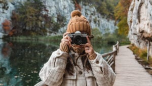 Photograph vs Picture: What's the Difference, and Does It Matter woman with camera taking a photo in nature