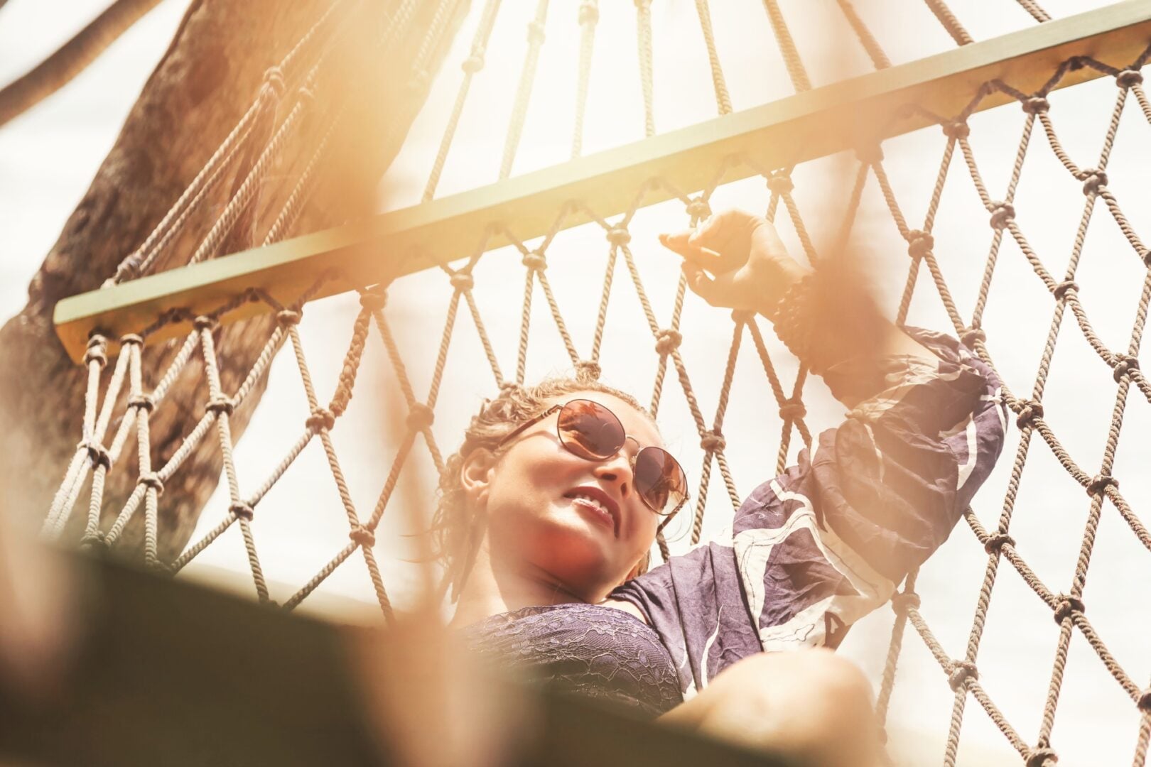 Face of pretty woman in sunglasses relaxing on hammock at tropical beach. Lifestyle portrait happy smiling female resting in hammock. Summer tropic vacation, travel tourism concept. Copy ad text space
