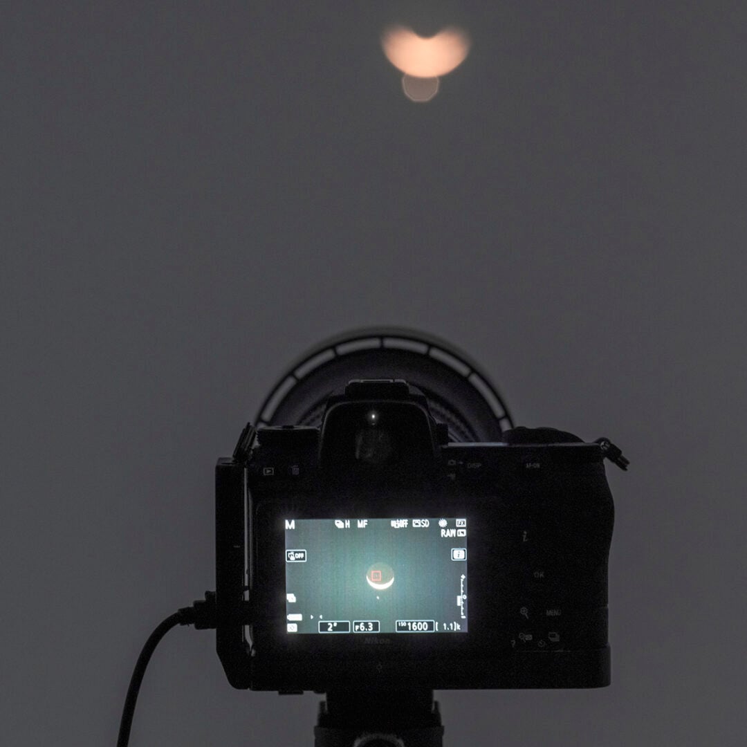 Use a telephoto lens or a telescope to photograph the event