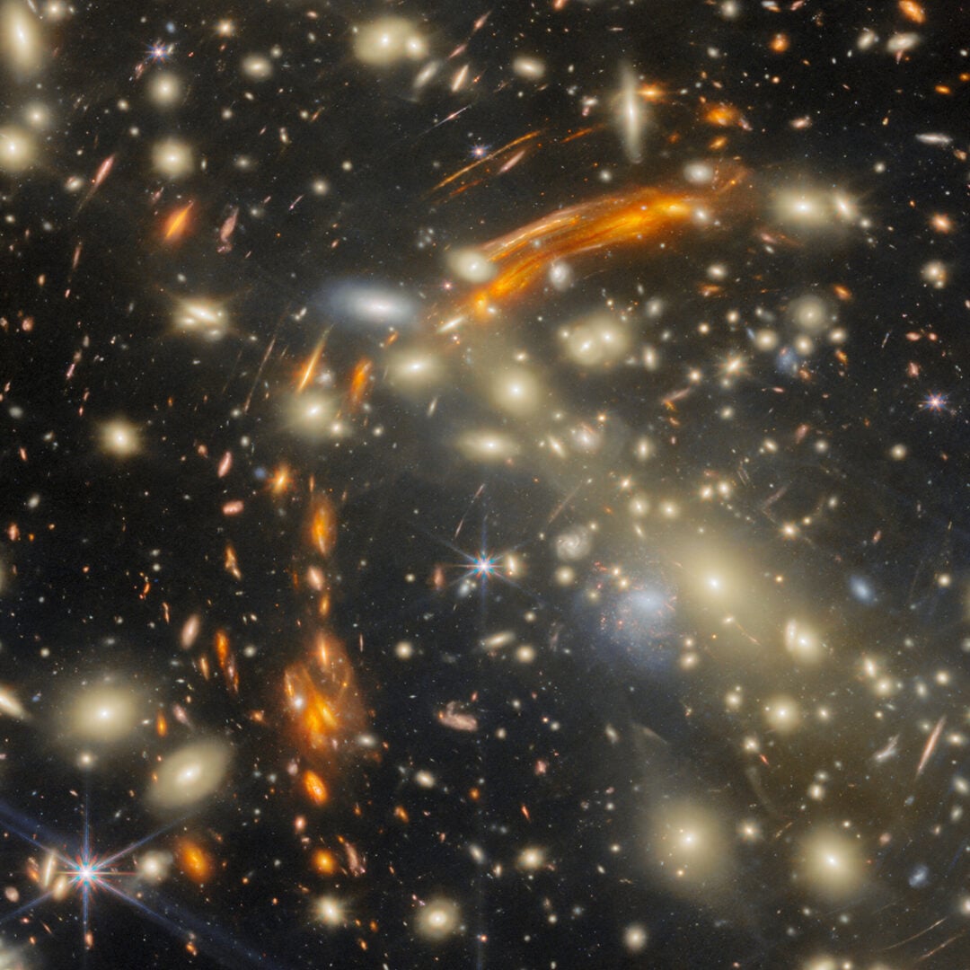 The orange arcs are the background galaxies, magnified by the foreground galaxy cluster. Credit: ESA/Webb, NASA & CSA, L. Furtak, S. Fujimoto